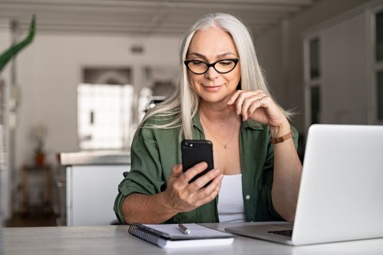 Femme utilisant un ordinateur et un téléphone.