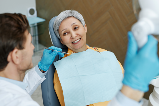 Dentiste avec patiente adulte en train de sourire.