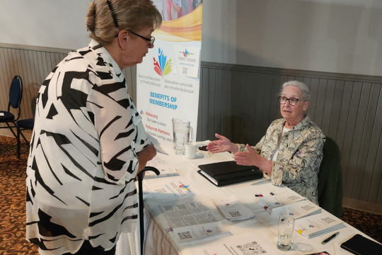 La présidente de la Section de Saskatoon et région, Myrene Mollison, en train de parler à un participan t au forum public sur les élections provinciales en Saskatchewan.