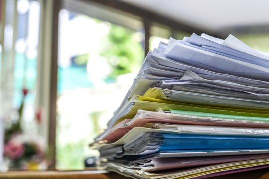 Pile de factures et de documents sur un bureau.