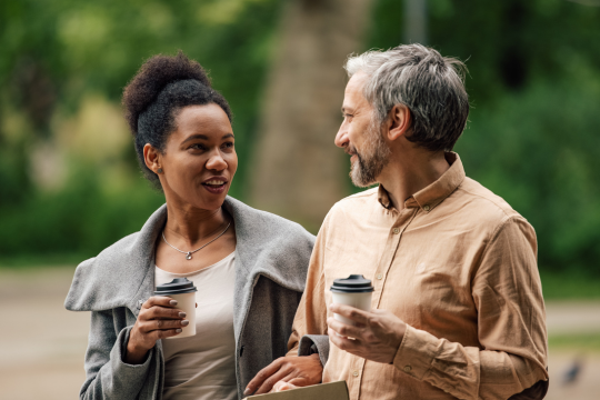 Deux amis se promenant ensemble, tasses de café à la main.